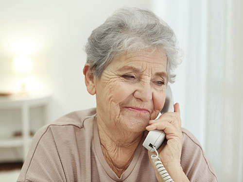 An elderly woman holds a phone