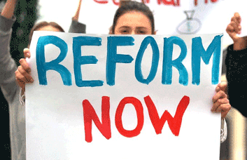 A photo of a person holding a sign that says Reform Now