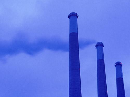 3 coal power plant smoke stacks on a blue background