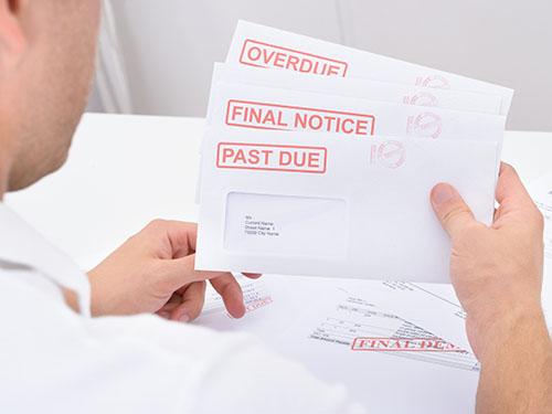 A man holds envelopes of over due bills