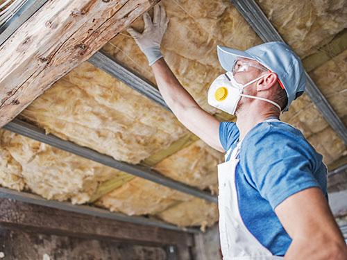 A man inspects insulation in a ceiling