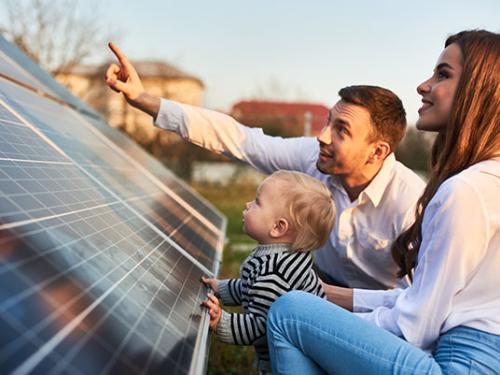 A family with a toddler look at a solar panel