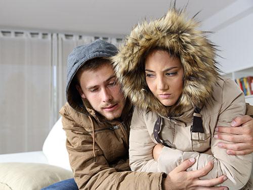 A couple wearing winter coats inside